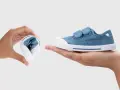 Manos muestran que son los escarpines: uno doblado y otro desplegado, de tela azul con velcro.