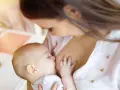 Bebé lactante, su pequeña mano aferrada al pecho. ¿Por qué un bebé recién nacido no orina? La respuesta está en su dieta líquida.