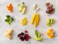 Variedad de alimentos para blw bebé 6 meses: zanahoria, calabacín, brócoli, pasta, mango, kiwi, aguacate, bayas, plátano y queso.