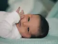Bebé con piel ligeramente azulada, posible cianosis, mira fijamente con sus grandes ojos oscuros.
