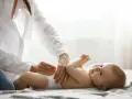 Manos cuidadosas cambian pañales a un bebé sonriente.