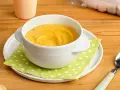Puré amarillo en un cuenco blanco, ideal para saber qué pescado puede comer un bebé de 6 meses.
