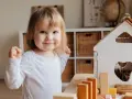 Niña sonriente jugando con bloques, un ejemplo de la evolución del lenguaje en bebés.