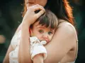 Bebé con chupete, acurrucado en brazos de su madre. Un momento tierno que nos hace pensar en cuando se inventó el chupete.