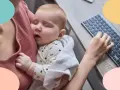 Mi bebe solo duerme en brazos mientras trabajo. Un tierno bebé duerme plácidamente en brazos, envuelto en una manta, mientras una mano teclea en un ordenador.