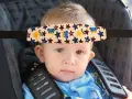 Un bebé con un arnés sujetacabezas con ositos y estrellas, esencial porque hay que sujetar la cabeza a los bebés en el coche.