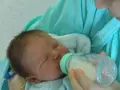 Bebé durmiendo mientras le dan leche con uno de los tipos de biberones.