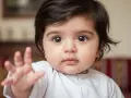 Bebé con ojos grandes y oscuros, mano extendida. Su nombre, Salma, significa paz.