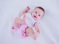 Bebé sonriente con un traje rosa y blanco, perfecto para inspirar nombres de niñas.