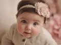 Bebé con diadema floral, sus ojos reflejan la ternura de nombres que significan amor.