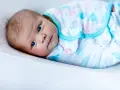 Un tierno bebé con ojos azules, envuelto en una mantita con ballenas, listo para arrullar.