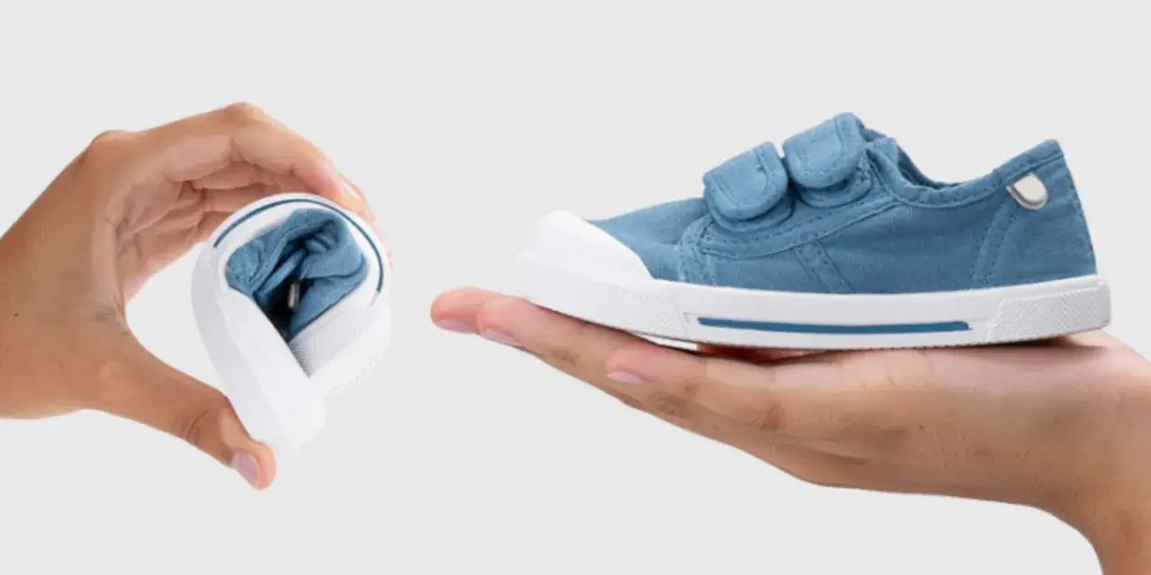 Manos muestran que son los escarpines: uno doblado y otro desplegado, de tela azul con velcro.