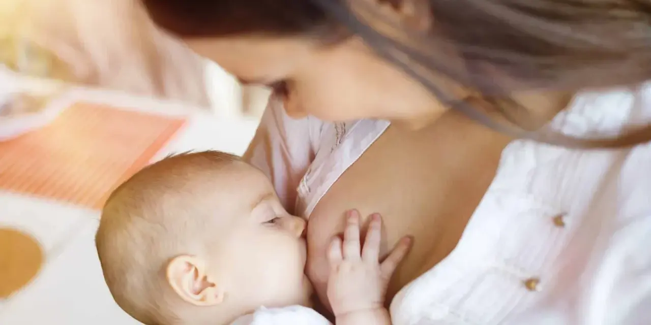 Bebé lactante, su pequeña mano aferrada al pecho. ¿Por qué un bebé recién nacido no orina? La respuesta está en su dieta líquida.