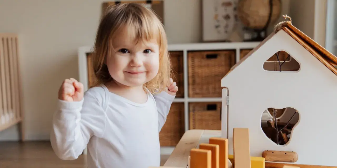 Niña sonriente jugando con bloques, un ejemplo de la evolución del lenguaje en bebés.