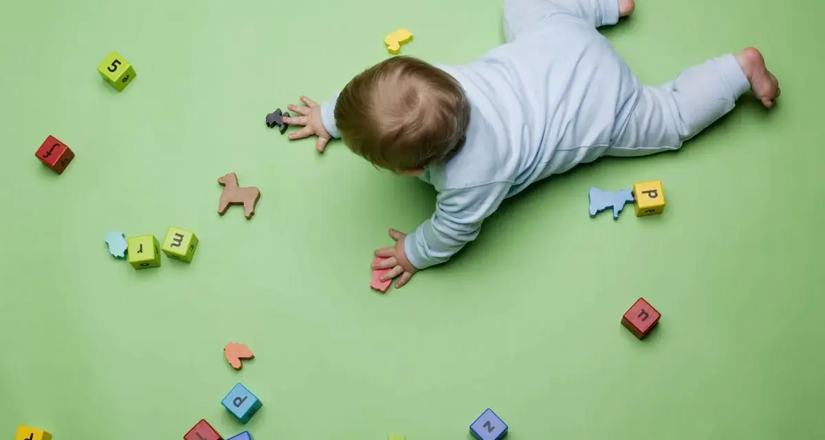 Bebé gateando entre bloques con letras y números, jugando con figuras de animales. Quizás buscando inspiración para nombres de niños originales.