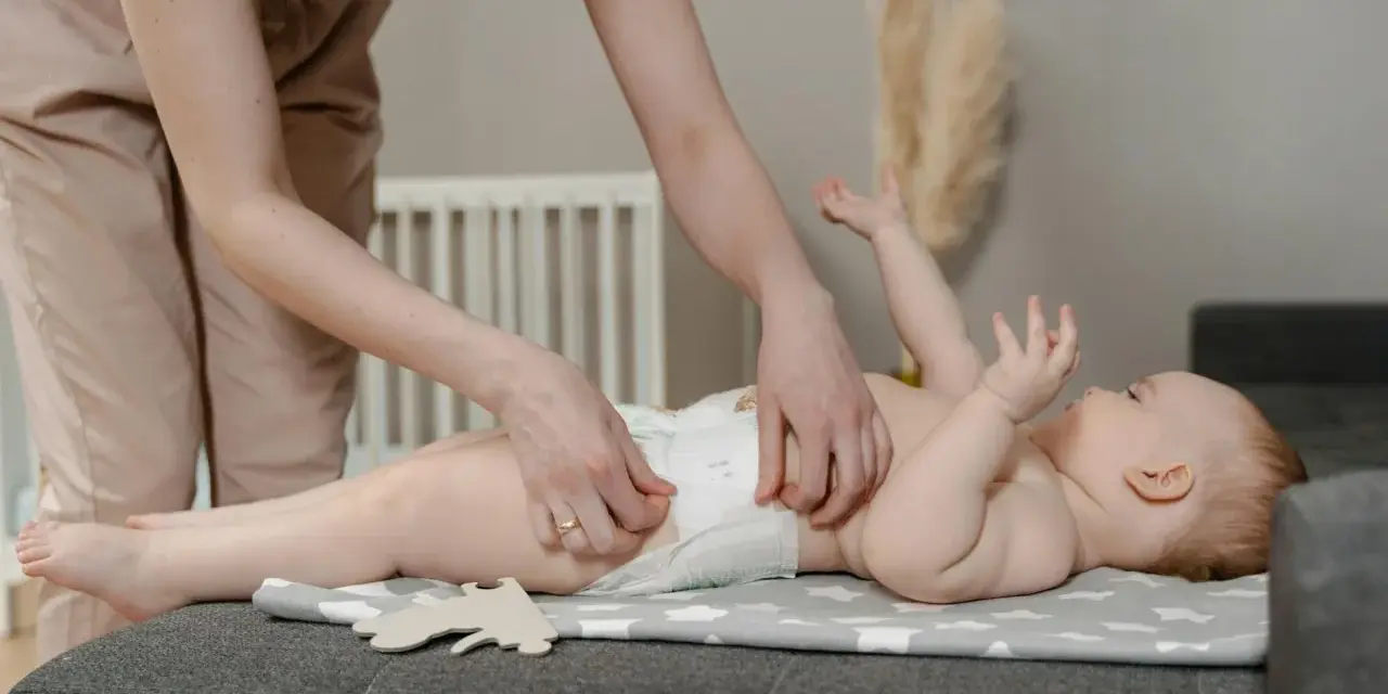 Madre cambiando pañal a su bebé. Preguntas sobre hasta cuando sacar gases bebe son comunes.