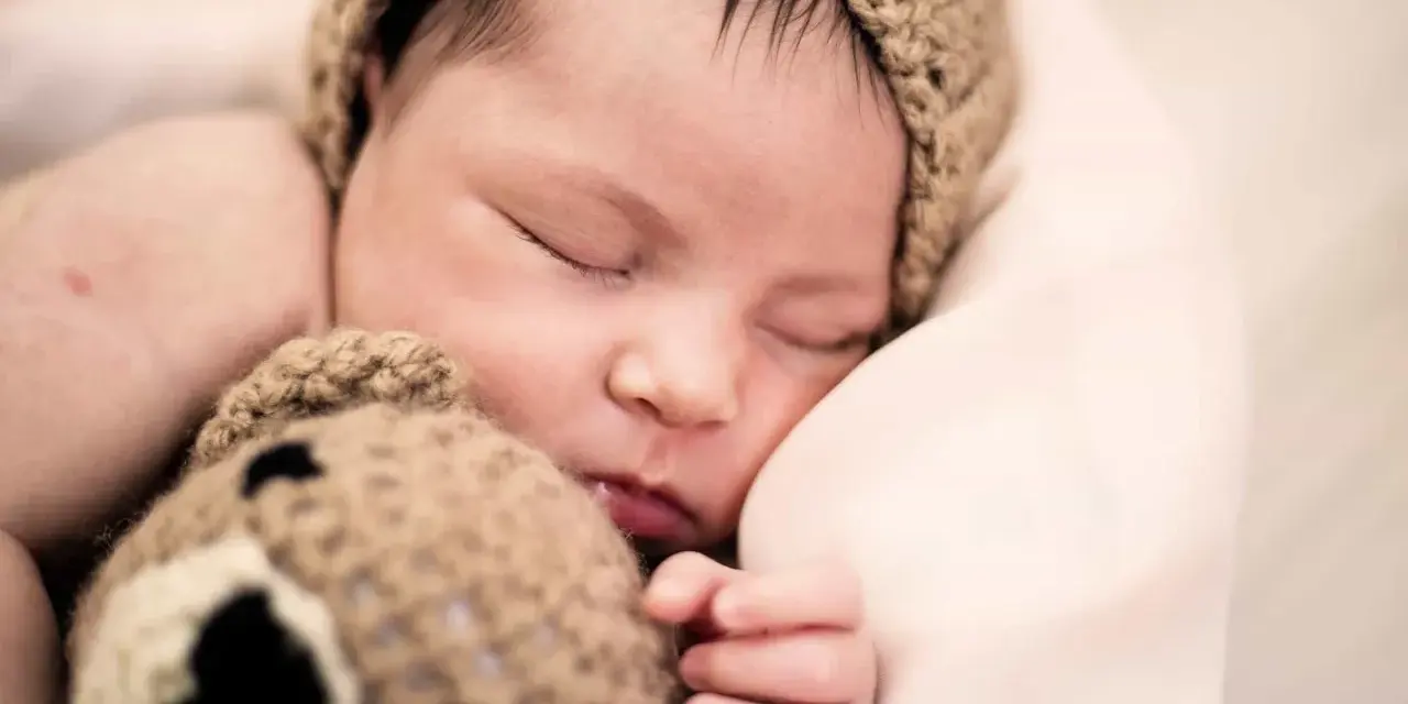 Bebé dormido con gorro de oso. ¿Cómo despertar a un bebé para que coma?