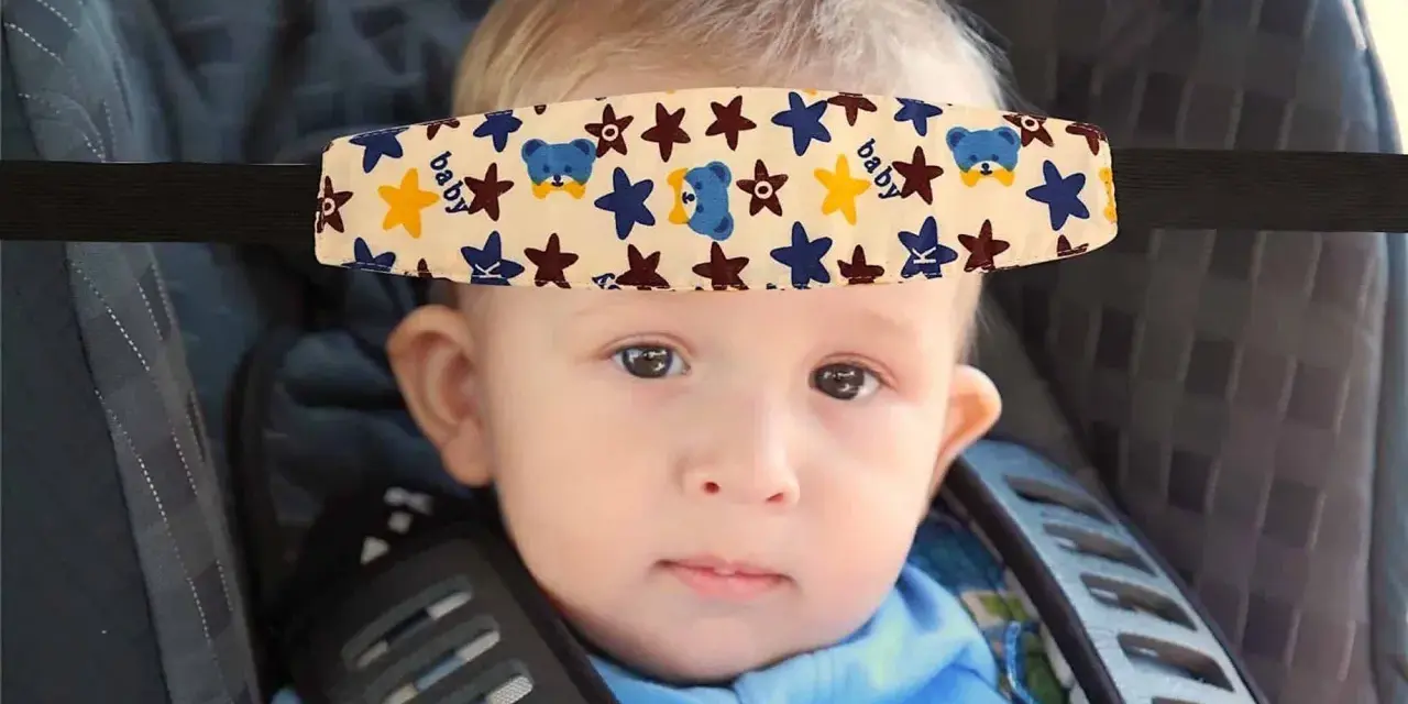 Un bebé con un arnés sujetacabezas con ositos y estrellas, esencial porque hay que sujetar la cabeza a los bebés en el coche.