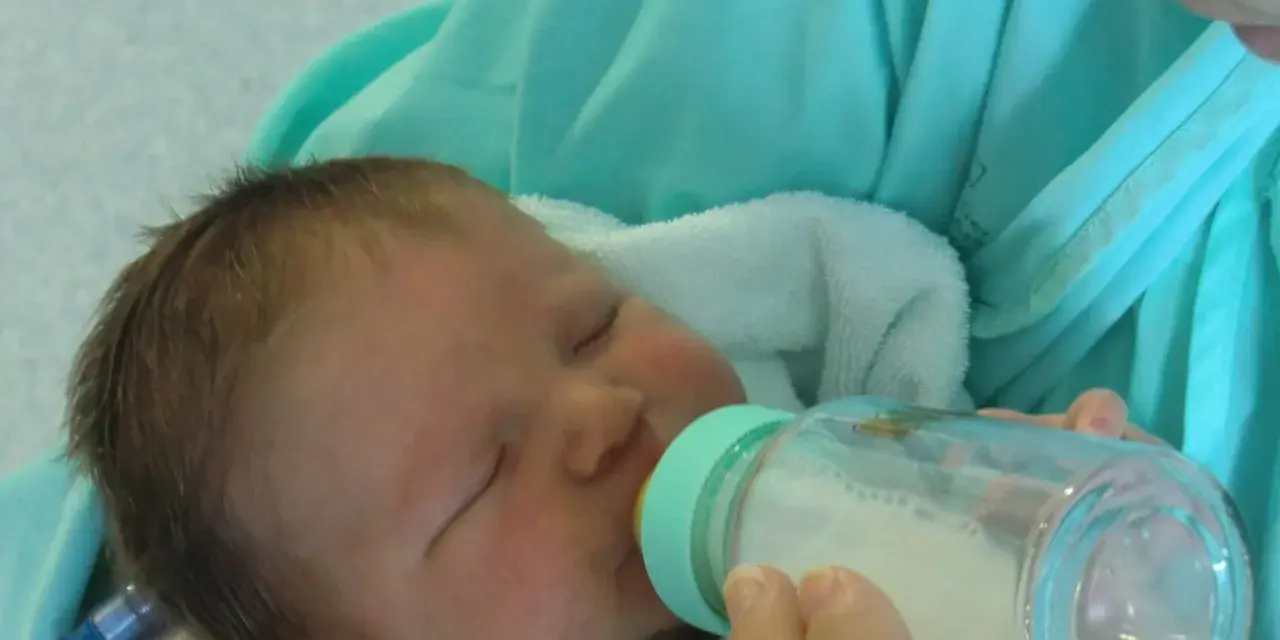 Bebé durmiendo mientras le dan leche con uno de los tipos de biberones.