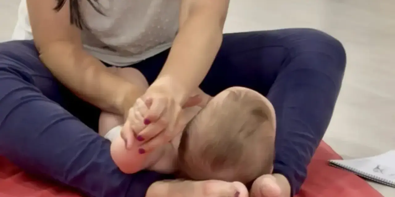 Manos cuidadosas realizan un masaje infantil en los pies de un bebé, fomentando la relajación y el vínculo.