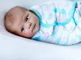 Un tierno bebé con ojos azules, envuelto en una mantita con ballenas, listo para arrullar.