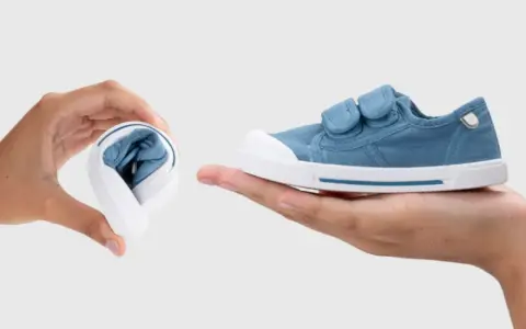 Manos muestran que son los escarpines: uno doblado y otro desplegado, de tela azul con velcro.