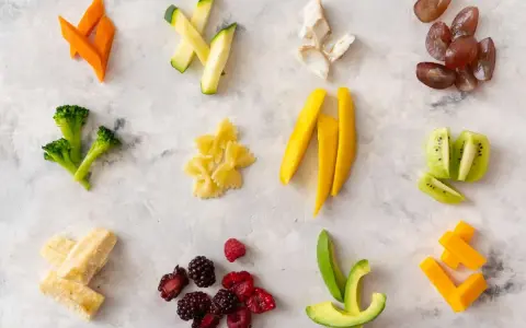 Variedad de alimentos para blw bebé 6 meses: zanahoria, calabacín, brócoli, pasta, mango, kiwi, aguacate, bayas, plátano y queso.