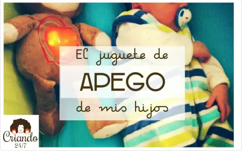 Un peluche con un corazón brillante, un bebé envuelto en mantas a rayas. El juguete de apego favorito de mis hijos.