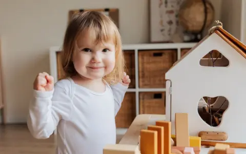 Niña sonriente jugando con bloques, un ejemplo de la evolución del lenguaje en bebés.