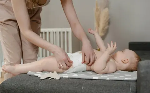 Madre cambiando pañal a su bebé. Preguntas sobre hasta cuando sacar gases bebe son comunes.