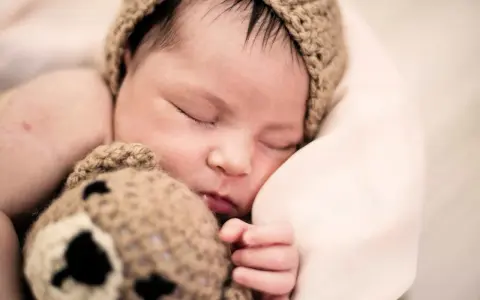 Bebé dormido con gorro de oso. ¿Cómo despertar a un bebé para que coma?