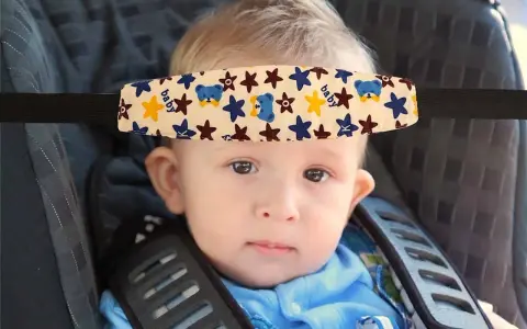 Un bebé con un arnés sujetacabezas con ositos y estrellas, esencial porque hay que sujetar la cabeza a los bebés en el coche.