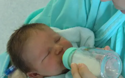 Bebé durmiendo mientras le dan leche con uno de los tipos de biberones.