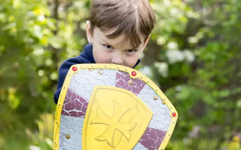 Niño con escudo de juguete, listo para la aventura. ¡Jugar al aire libre ayuda a subir defensas niños!