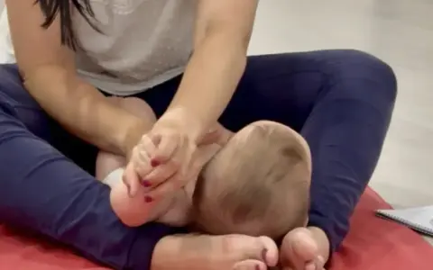 Manos cuidadosas realizan un masaje infantil en los pies de un bebé, fomentando la relajación y el vínculo.