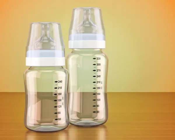 Dos biberones, uno de cristal o plástico más pequeño y otro más grande, con marcas de medición.