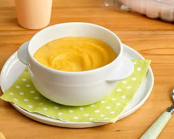 Puré amarillo en un cuenco blanco, ideal para saber qué pescado puede comer un bebé de 6 meses.
