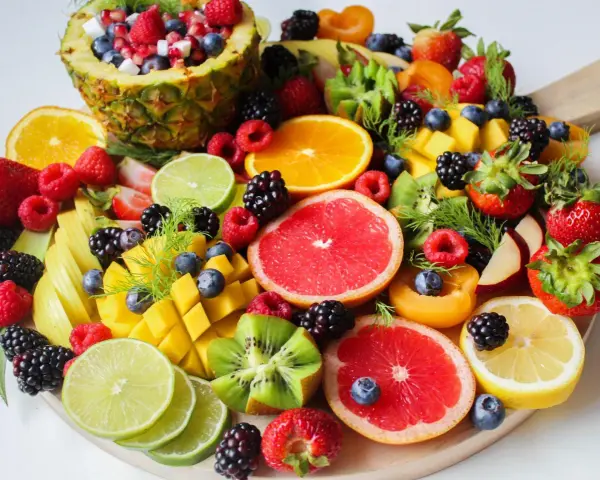 Tabla de frutas de primavera: piña, naranjas, fresas, frambuesas, moras, arándanos, mango, kiwi, pomelo y limón.