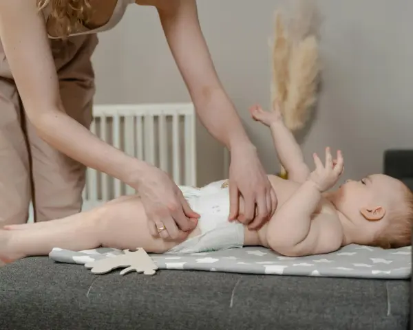 Madre cambiando pañal a su bebé. Preguntas sobre hasta cuando sacar gases bebe son comunes.