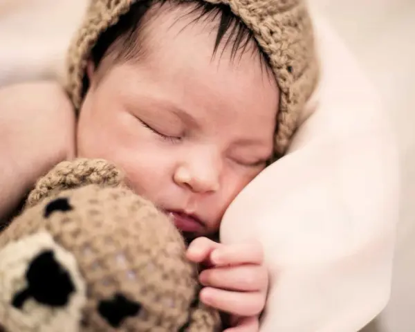 Bebé dormido con gorro de oso. ¿Cómo despertar a un bebé para que coma?