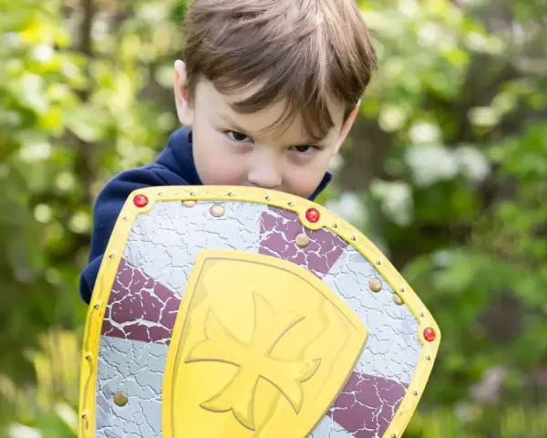 Niño con escudo de juguete, listo para la aventura. ¡Jugar al aire libre ayuda a subir defensas niños!