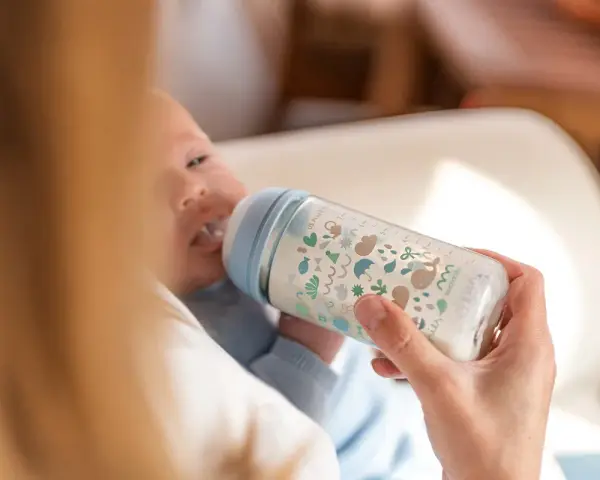 Bebé de 5 meses tomando biberón. La cantidad de biberones que toma un bebé de 5 meses varía, pero este parece disfrutar el suyo.