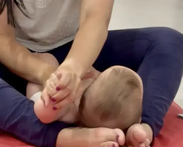 Manos cuidadosas realizan un masaje infantil en los pies de un bebé, fomentando la relajación y el vínculo.
