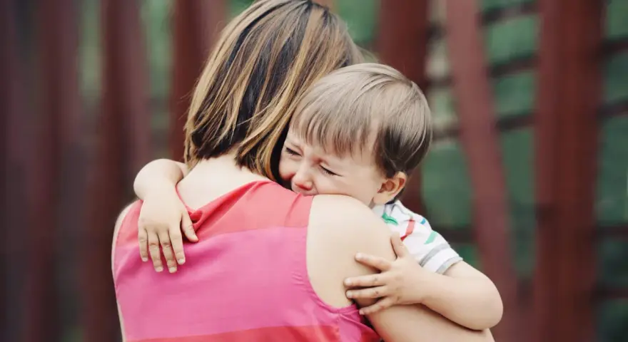 Un niño llora aferrado a su madre. A veces, los bebés rechazan a algunas personas por instinto o por no sentirse seguros.