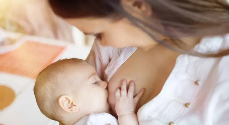 Bebé lactante, su pequeña mano aferrada al pecho. ¿Por qué un bebé recién nacido no orina? La respuesta está en su dieta líquida.