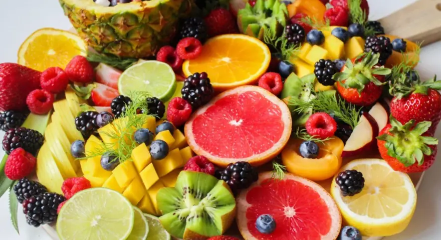 Tabla de frutas de primavera: piña, naranjas, fresas, frambuesas, moras, arándanos, mango, kiwi, pomelo y limón.