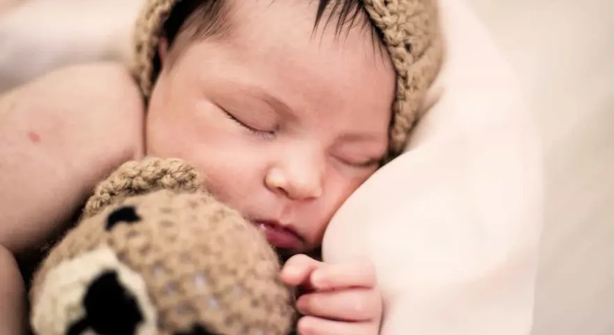 Bebé dormido con gorro de oso. ¿Cómo despertar a un bebé para que coma?