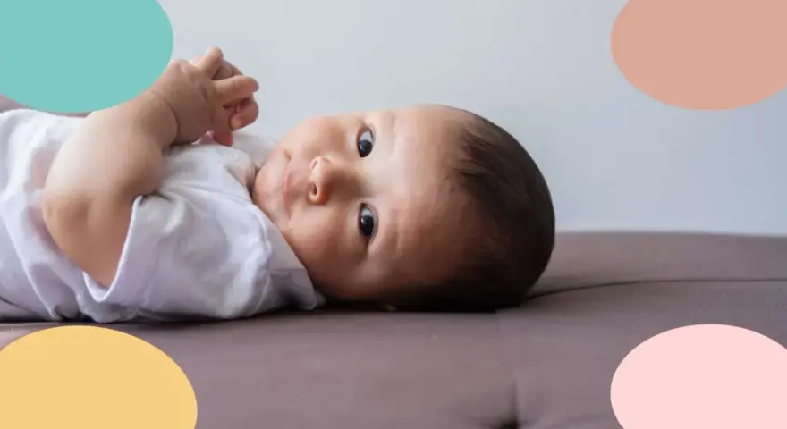 Un bebé de 6 meses, con ojos curiosos, parece estar soñando despierto mientras descansa sobre un sofá.