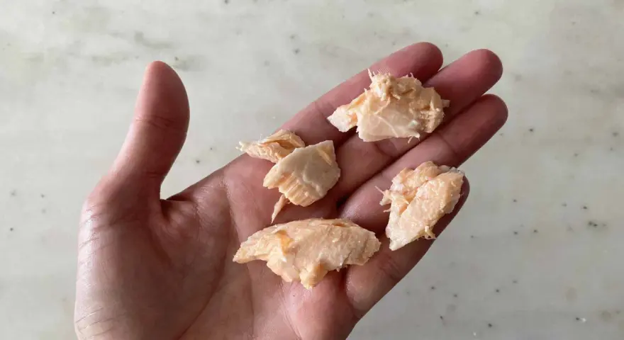 Trozo de salmón desmenuzado en una mano, ideal para saber cuándo dar salmón a un bebé.
