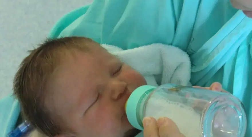 Bebé durmiendo mientras le dan leche con uno de los tipos de biberones.